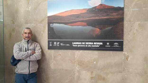 Picture of Bopi Biddanda leaning by a picture of the mountain lakes of Sierra Nevada